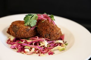 crab cake and slaw on a white dish with black background