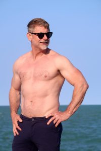 Shirtless man in his 50s with sunglasses and hands on hips