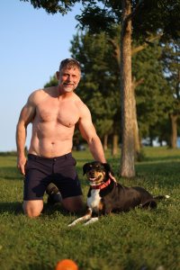 Shirtless man in his 50s with dog