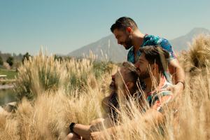 Throuple laughing in a field