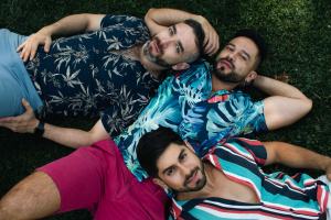 Throuple lying on grass in park